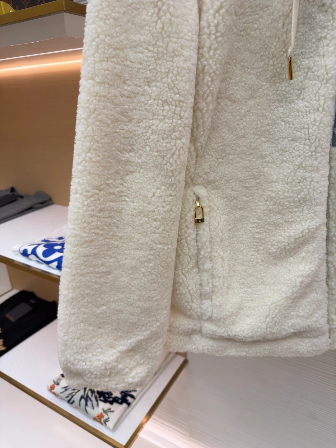 LOUIS VUITTON Letter jacquard splicing lamb wool ski hooded jacket ●Original version: purchased and developed by 26909 ●Item number: 1682241-C35 ●Fabric: lamb wool fabric ●Technology: jacquard production ●Color: off-white ●Version: fitted version ●Weight: about 1245 grams ●Size: 34-36-38-40-42-44 ●Description: The main body of this lamb wool spliced denim jacket is made of imported imitation lamb wool fabric, which has been processed by carding and shaping processes. The wool feels fluffy and soft and is not easy to shed and pill. The fabric has a uniform weight and has both warmth retention and breathability. The neckline, placket and chest pockets are spliced ​​with classic presbyopic denim. The denim is enzymatically washed to create a natural aged texture. The presbyopic pattern is embossed, making the texture three-dimensional and not easy to fall off. The body adopts a loose hooded fit, with a built-in shaping lining on the brim and an adjustable drawstring design; a custom metal zipper is used at the placket, and the chain teeth are gold-plated for smooth pulling and anti-oxidation. The edges of the pockets are reinforced with double stitching, and the splicing of lambswool and denim is made by hand caulking. The stitching is fine and smooth. Every detail is strictly controlled, showing the craftsmanship and quality of high-end clothing. The overall wiring is straight and delicate, the fabric is comfortable and soft, and the color is consistent without color difference. It can be matched with the same style to create a fashionable look and control various occasions. Customized accessories, complete with three standards, same style for men and women!